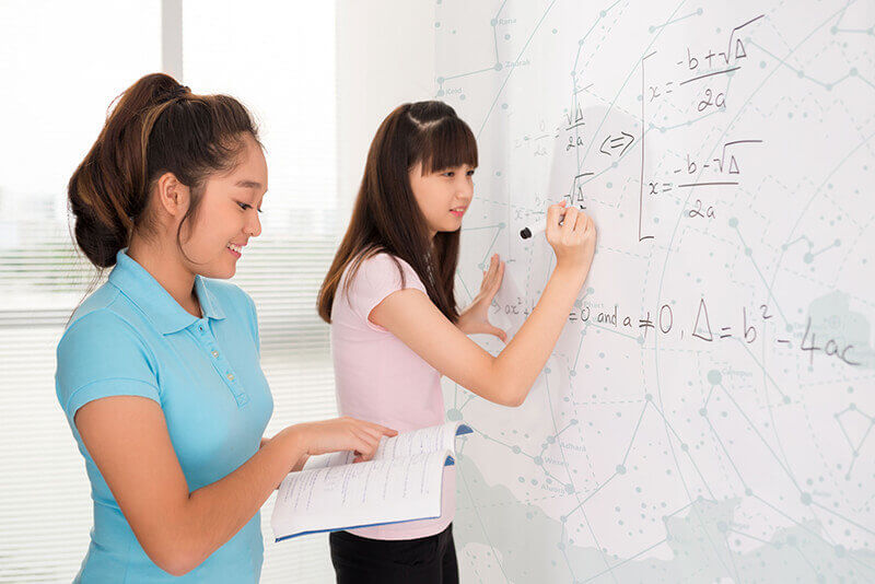 Two female students writing on the white board