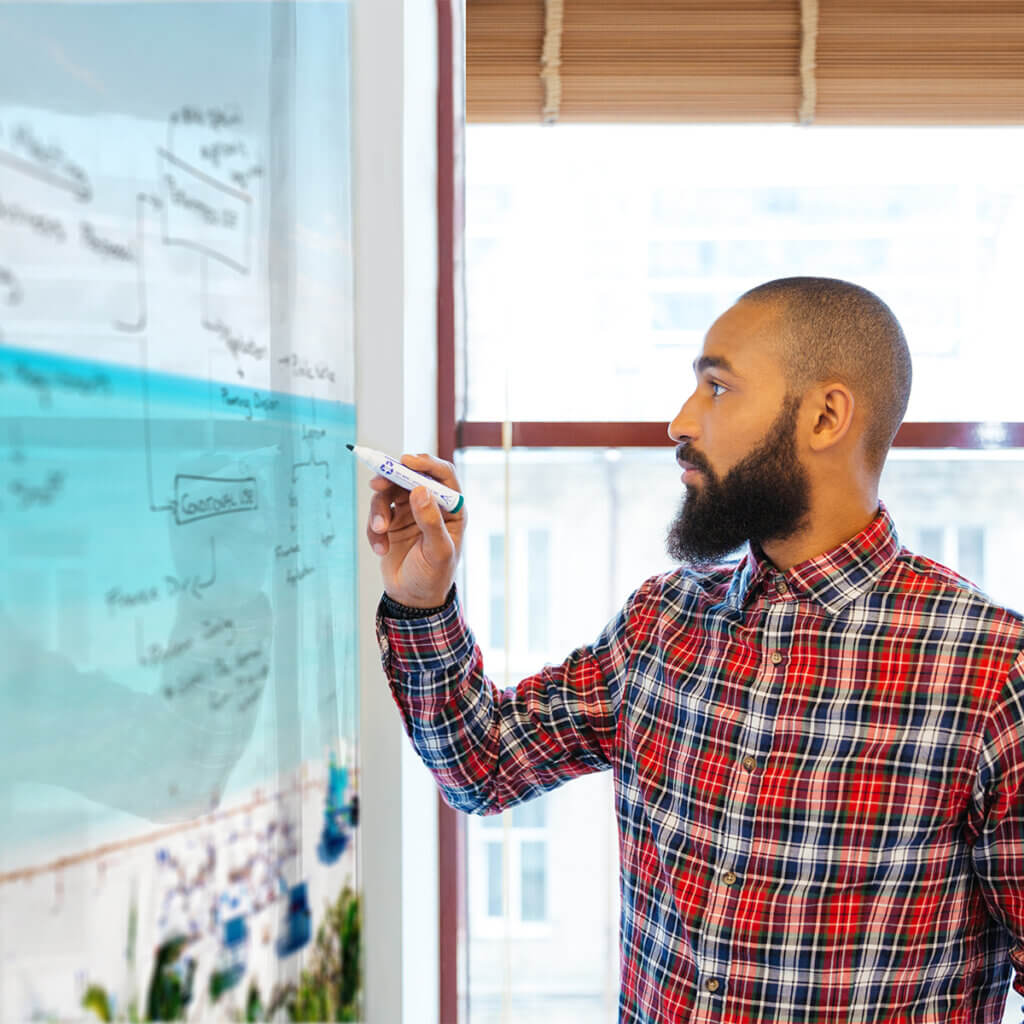 Image of Profile of handsome african man with beard standing and writing on whiteboard